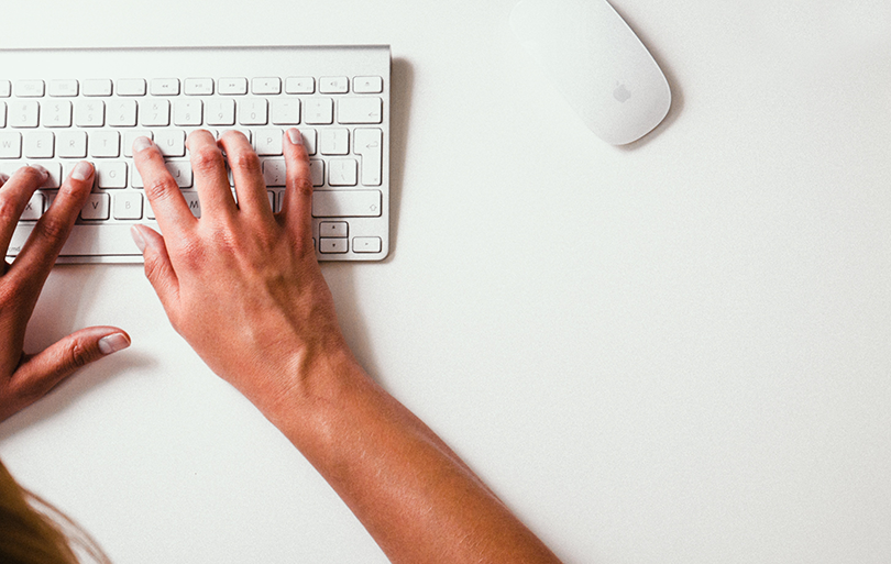 Photo of hands on a keyboard and a mouse.